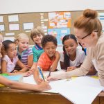 38074808 - teacher and pupils working at desk together at the elementary school