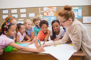 38074808 - teacher and pupils working at desk together at the elementary school